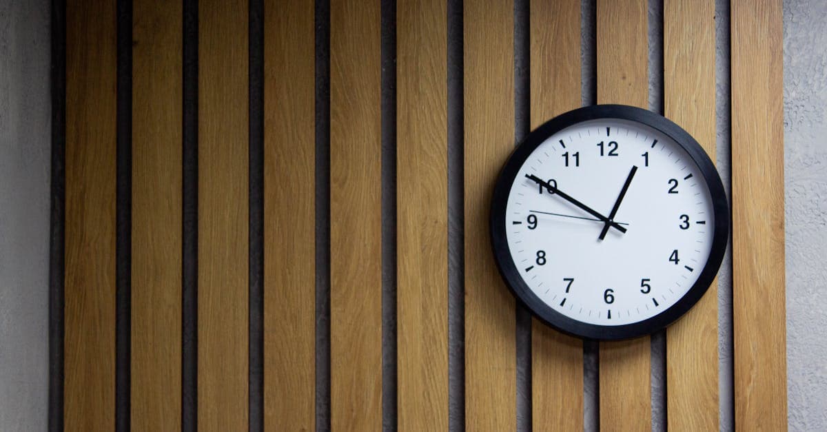 Team members collaborating around a table with a laptop showing timesheet data